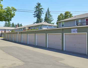 A row of garages with white garage doors in front of houses